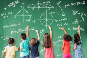 Students solving math equations on a chalkboard.