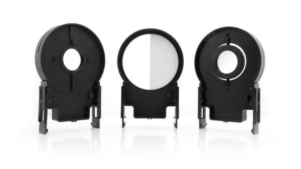 A group of three black plastic holders with one holding a white object.