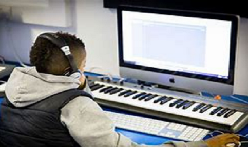 A young boy sitting in front of a computer keyboard.
